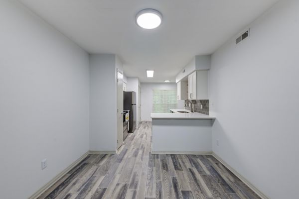 A galley kitchen with light wood-look flooring and a small breakfast bar.