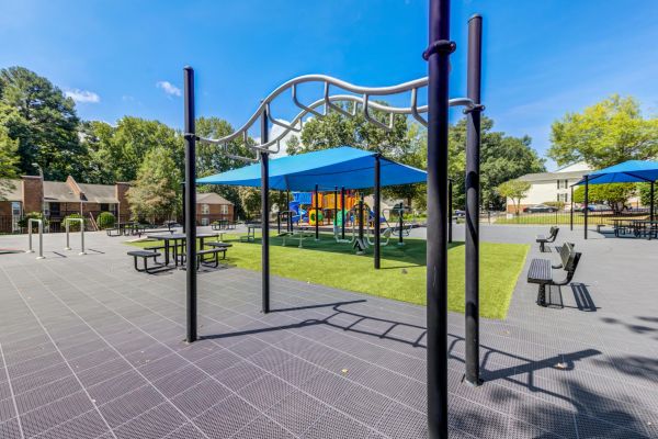 Outdoor playground with monkey bars and a blue shade canopy.