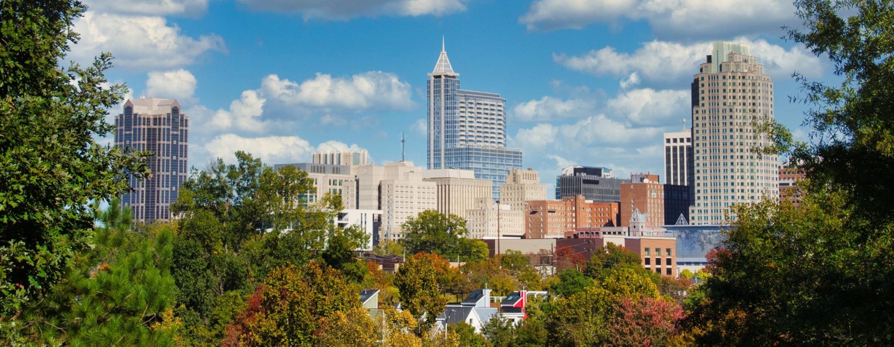 City skyline featuring the Wells Fargo Capitol Center tower under a blue sky with clouds.